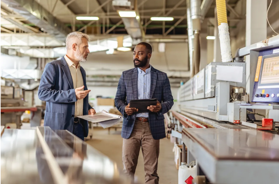 Two technicians inspecting industrial machinery with tablet